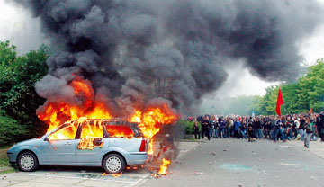 ロストック市内のデモにおいて反対派による放火により炎上する車両（6月、ドイツ）（時事）