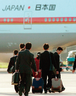 日本へ向かう政府専用機へ荷物を持って歩く拉致被害者の子どもたち（時事）